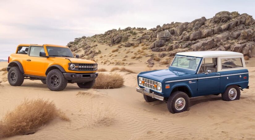 A yellow 2021 Ford Bronco and a blue 1996 Ford Bronco is shown parked off-road.