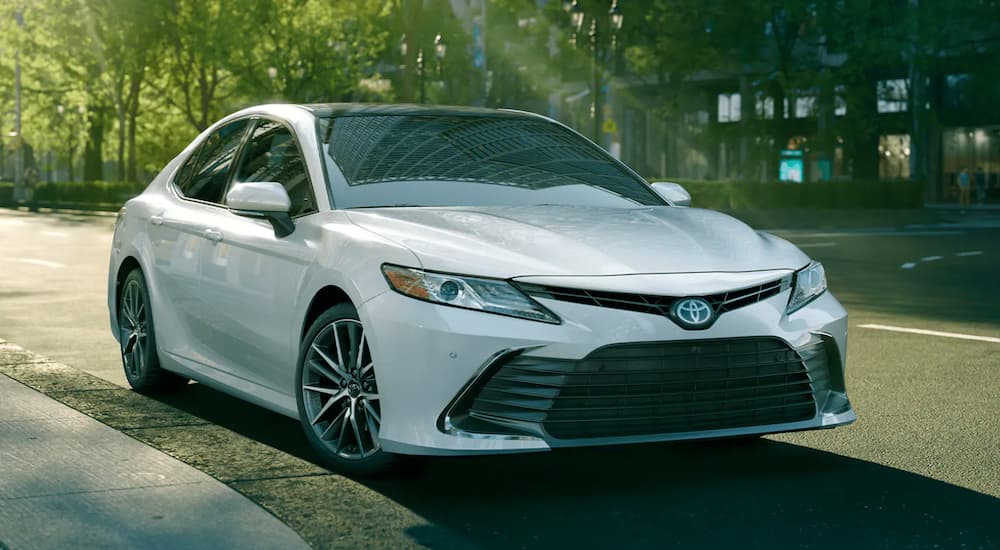 A white 2021 Toyota Camry is shown parked on the side of a street.
