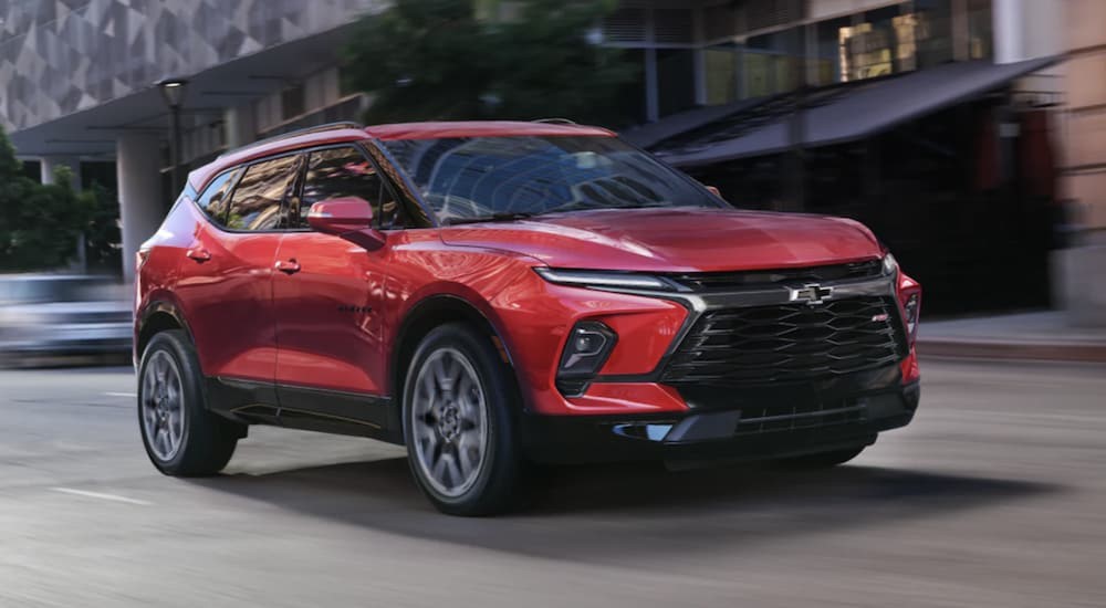 A red 2023 Chevy Blazer RS is shown driving on a city street.