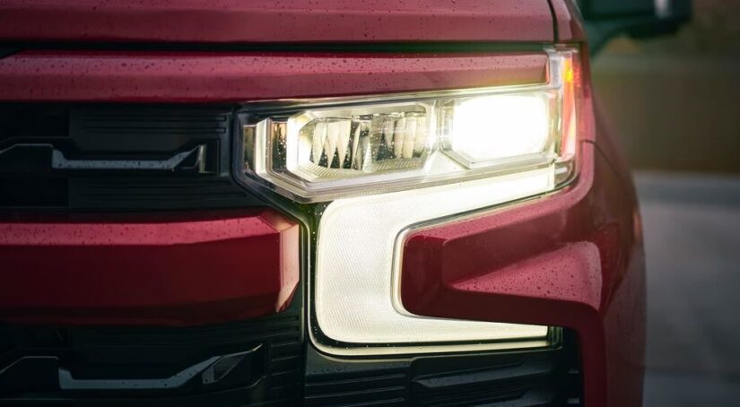 A close-up on the headlight of a red 2023 Chevy Silverado 1500 WT for sale is shown.