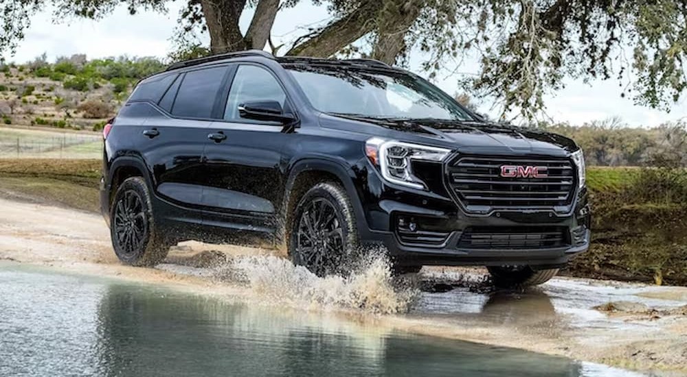 A black 2023 GMC Terrain SLT is shown driving on a watery road.