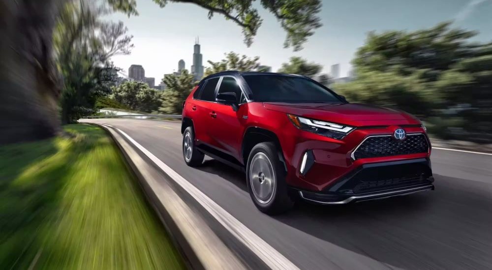 A red 2023 Toyota RAV4 Prime is shown driving.