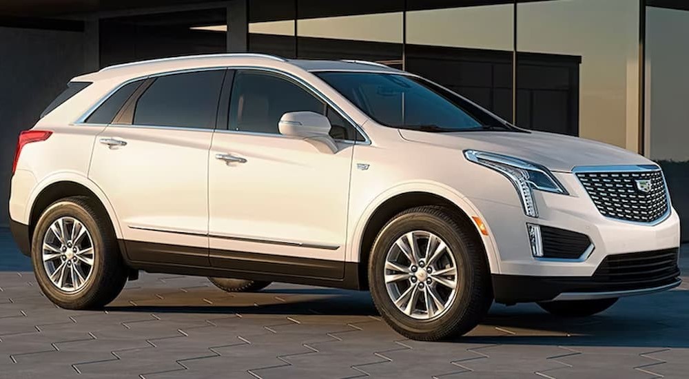 A white 2024 Cadillac XT5 is shown parked near a building.