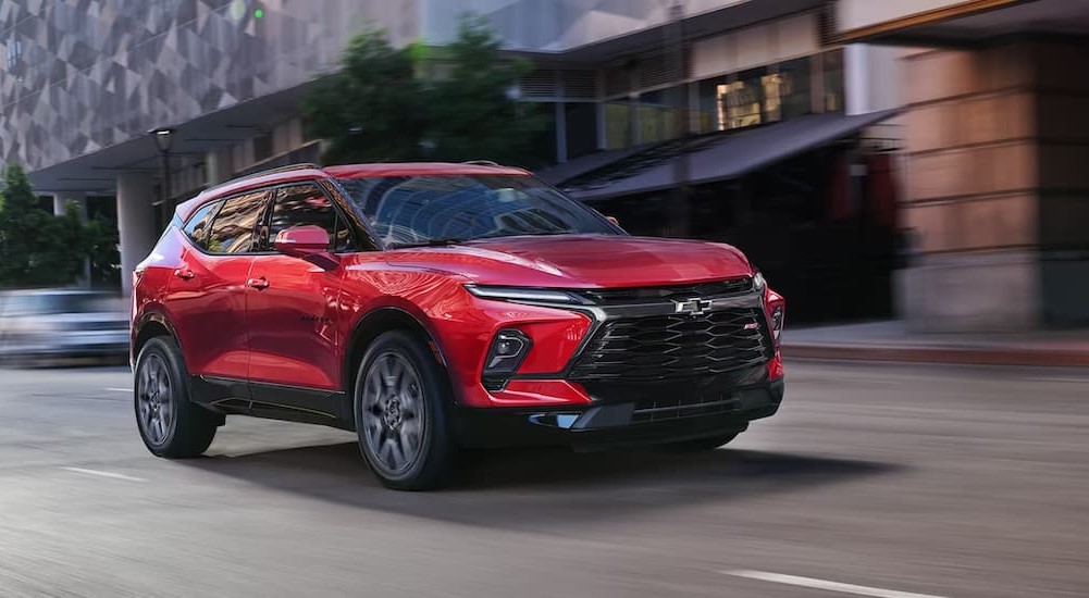 A red 2024 Chevy Blazer RS is shown driving on a city street.