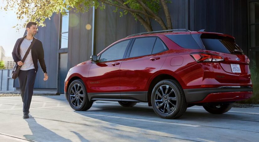 A red 2024 Chevy Equinox is shown parked near a sidewalk after winning a 2024 Chevy Equinox vs 2024 Mitsubishi Eclipse Cross competition.