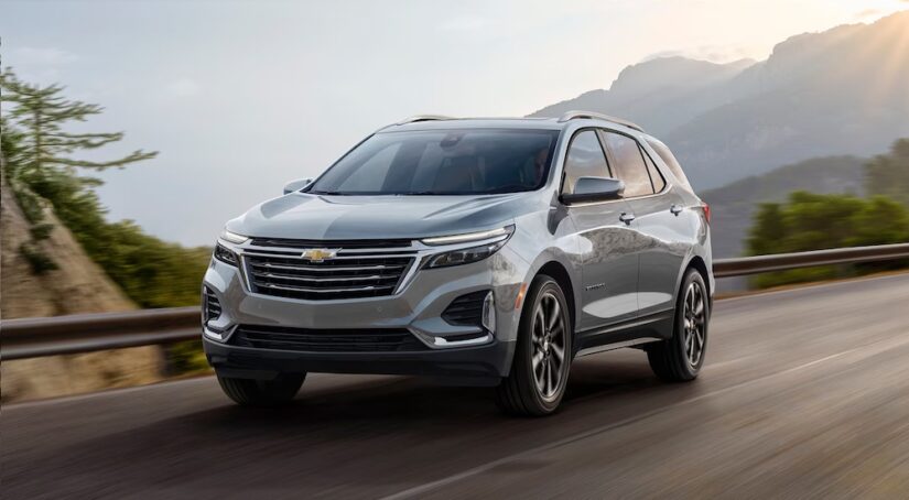 A silver 2024 Chevy Equinox is shown driving on a road from a 2024 Chevy Equinox vs 2024 Ford Escape competition.