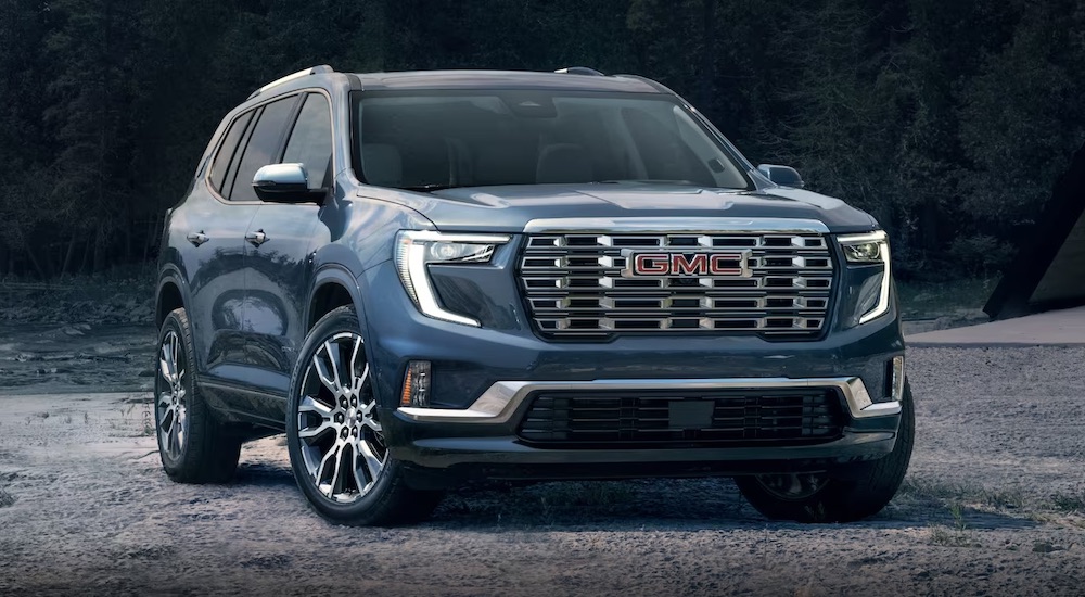 A blue 2024 GMC Acadia Denali is shown parked off-road.
