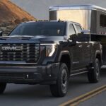 A black 2024 GMC Sierra 2500HD Denali is shown towing a trailer.