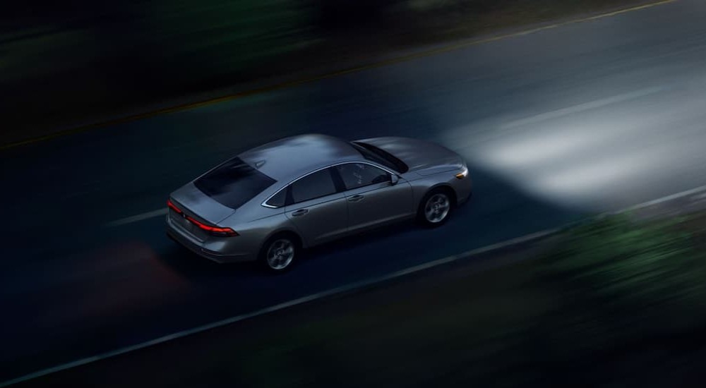 A silver 2024 Honda Accord is shown driving at night.