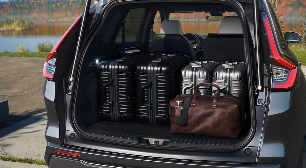 Suitcases are shown in the cargo area of a gray 2024 Honda CR-V Hybrid.