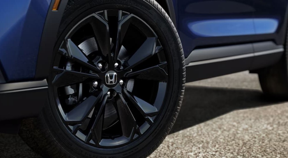 The black wheel of a blue 2024 Honda CR-V ST Hybrid is shown.