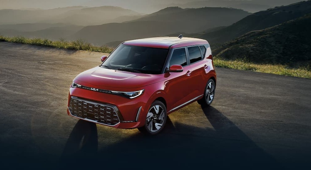 A red 2024 Kia Soul is shown parked on top of a hill.
