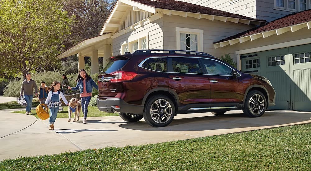 A red 2024 Subaru Ascent is shown parked on a driveway near a family.