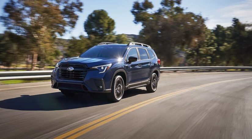 A blue 2024 Subaru Ascent for sale is shown driving on a highway.