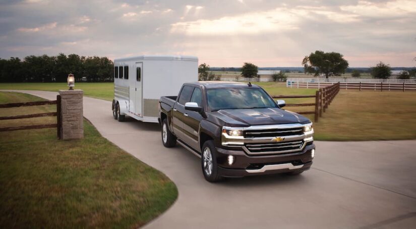 One of the most popular used Chevy trucks for sale, a black 2017 Chevy Silverado 1500, is shown towing a trailer.
