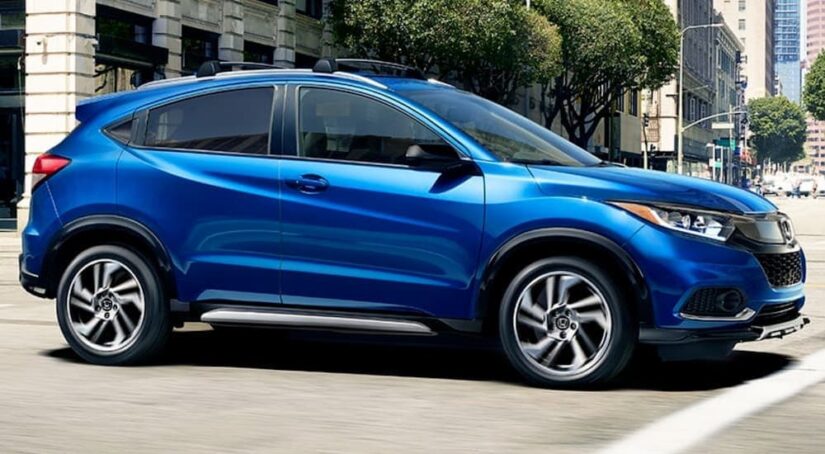 One of many popular used SUVs for sale, a blue 2020 Honda HR-V Sport, is shown driving on a city street.