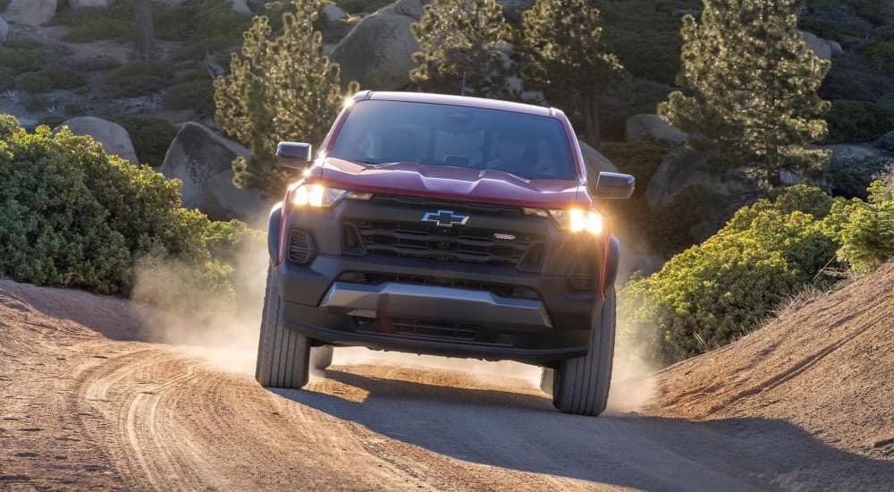 A red 2023 Chevy Colorado Trail Boss is shown driving down a trail.