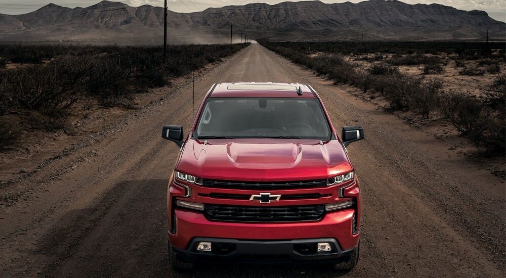 A red 2022 Chevy Silverado 1500 RST is shown driving down a dirt road.