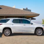 A white 2023 Chevy Traverse is shown parked near a house after viewing several used Chevy SUVs for sale.