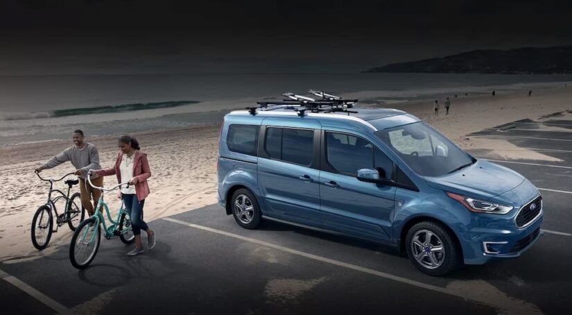 A blue 2023 Ford Transit Connect Passenger Wagon is shown parked near an ocean.