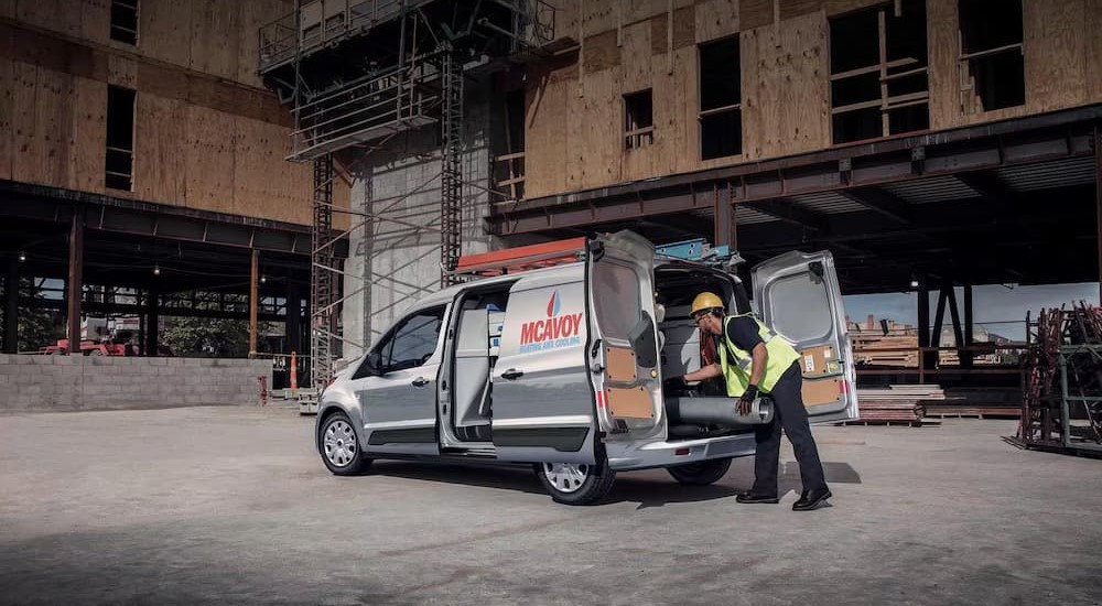 A silver 2023 Ford Transit Connect Cargo Van is shown parked near a construction site.