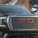 A close-up on the grille of a black 2024 GMC Yukon Denali is shown after visiting a Fayetteville GMC dealer.