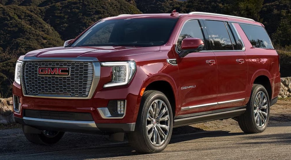 A red 2023 GMC Yukon Denali is shown parked on the side of a dirt road.