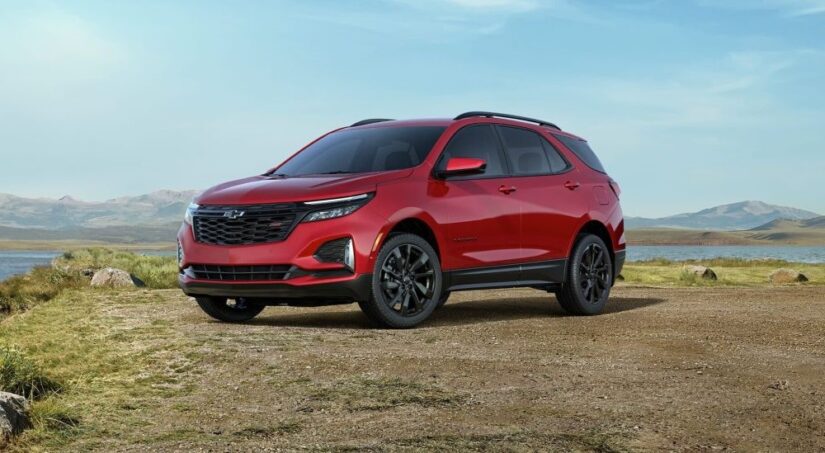 A red 2024 Chevy Equinox RS is shown parked near a lake after a 2024 Chevy Equinox vs 2024 Mitsubishi Eclipse Cross comparison.