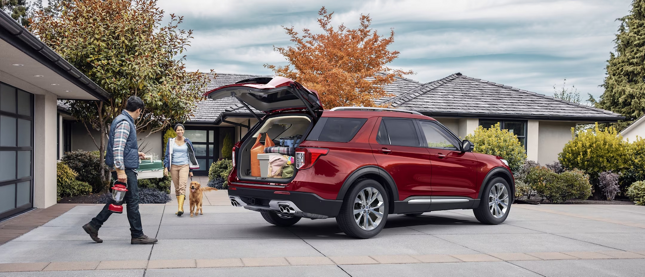 A red 2024 Ford Explorer Platinum is shown parked near a dog.