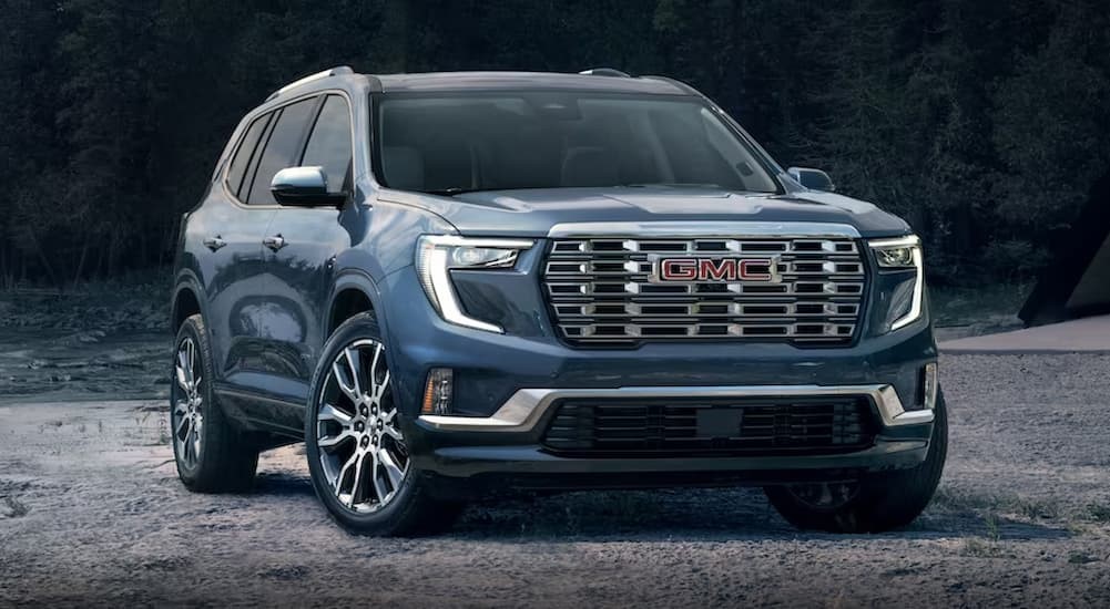 A blue 2024 GMC Acadia is shown parked off-road.