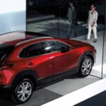 A person is shown walking near a red 2024 Mazda CX-30.