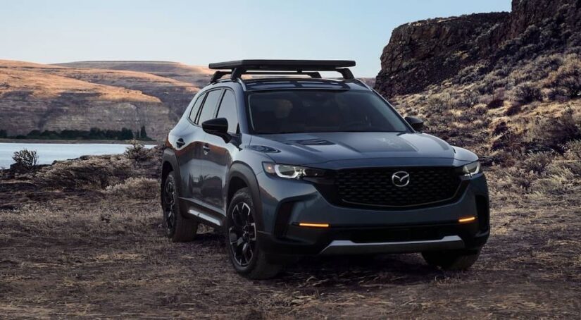 A grey 2024 Mazda CX-50 is shown driving off-road after visiting a Mazda dealer.