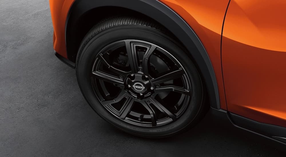 A close-up of a wheel on an orange 2024 Nissan Kicks is shown.