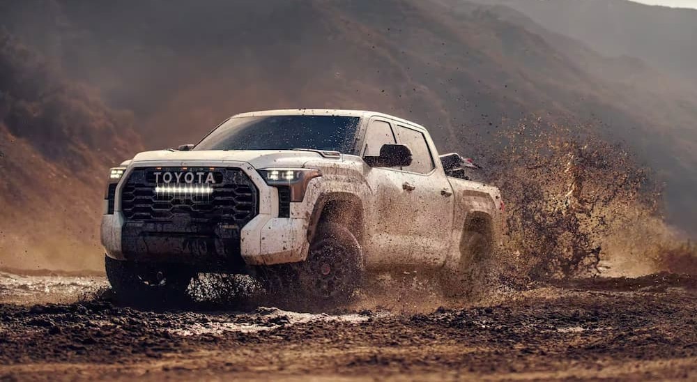 A white 2024 Toyota Tundra is shown driving off-road.