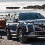 A black 2025 Hyundai Palisade towing a boat out of a lake.