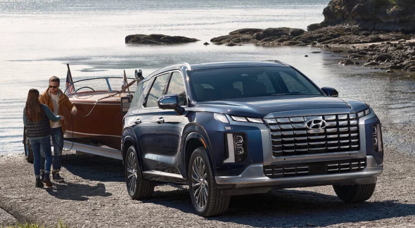 A black 2025 Hyundai Palisade towing a boat out of a lake.