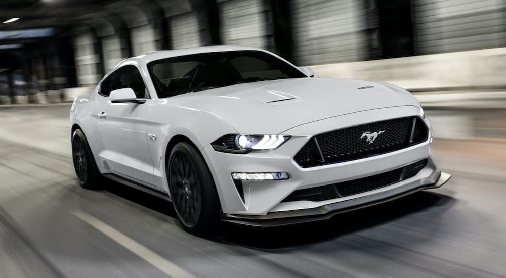 A white 2020 Ford Mustang GT is shown driving in a tunnel.