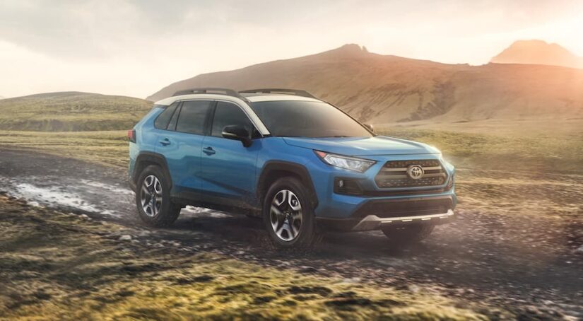 A blue 2020 Toyota RAV4 is shown driving on a muddy path after visiting a used Toyota Dealer near Vinings.