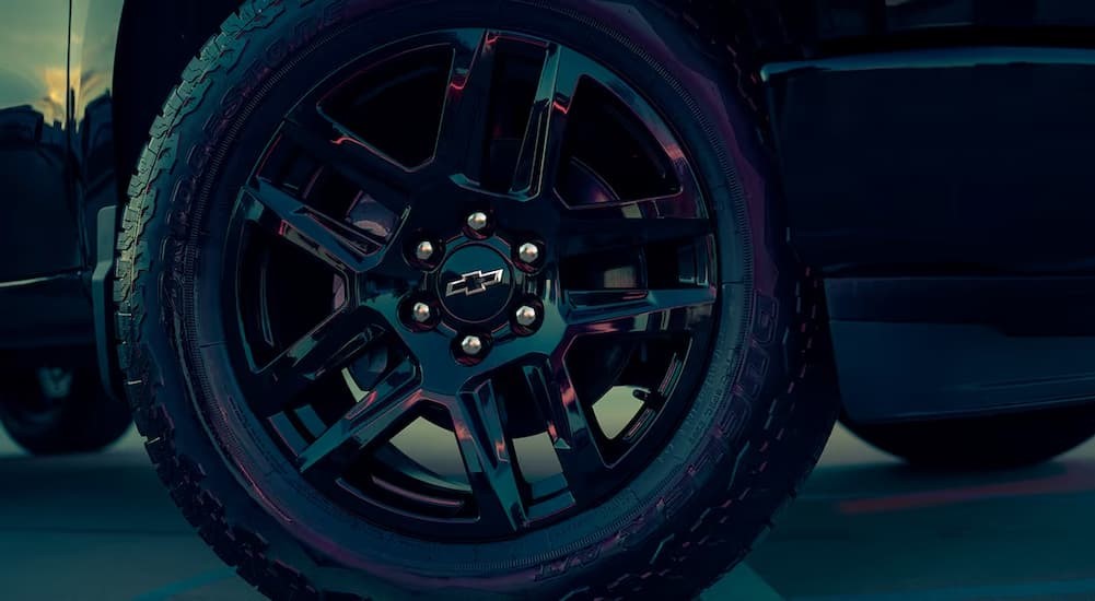 A close-up of the wheel on a black 2023 Chevy Silverado 1500 is shown.