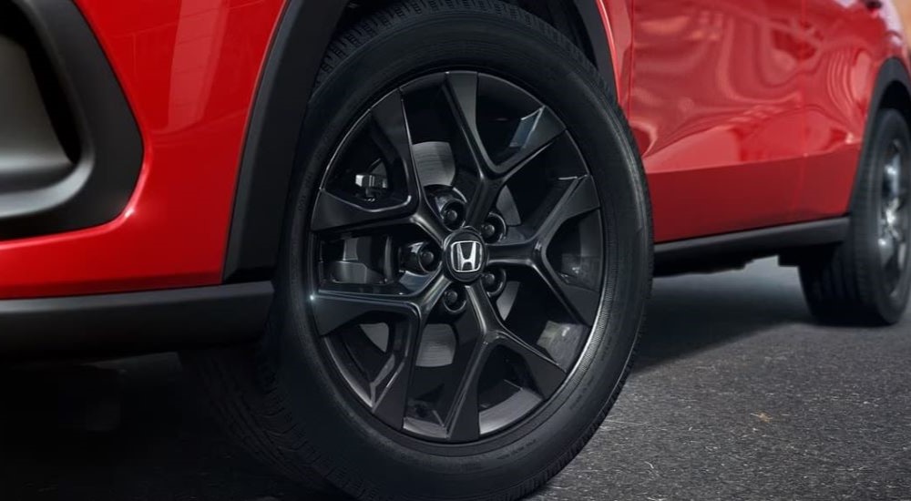 A close-up on the wheel of a red 2023 Honda HR-V Sport is shown.