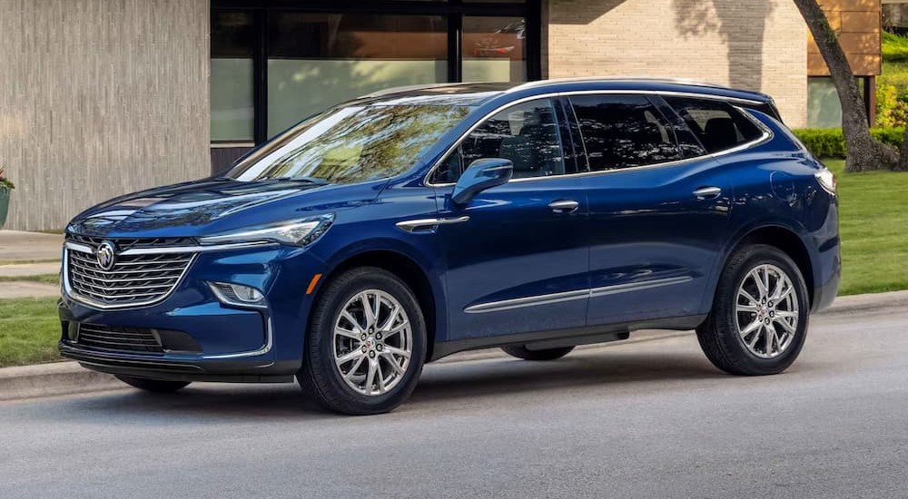 A blue 2024 Buick Enclave is shown parked near a building.
