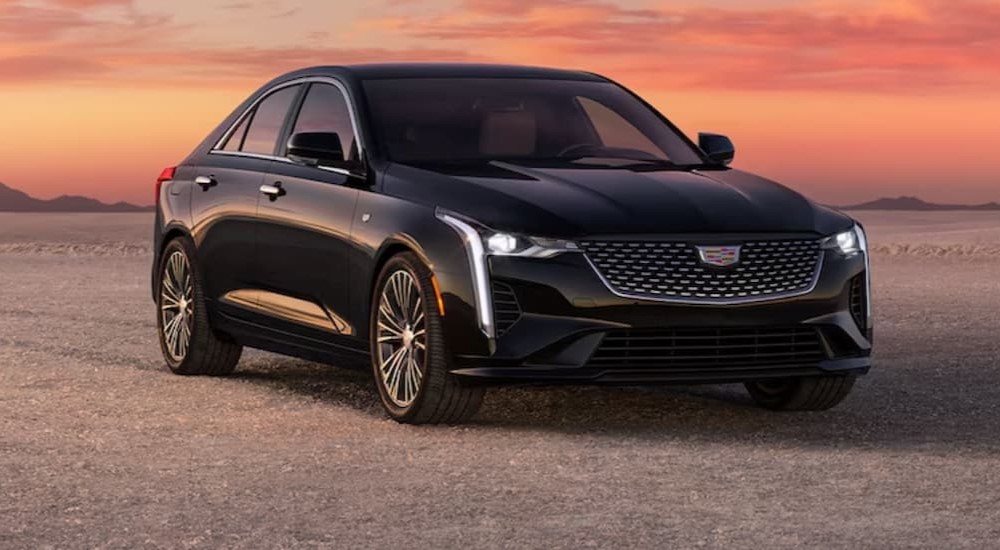 A black 2024 Cadillac CT4 is shown parked on sand.