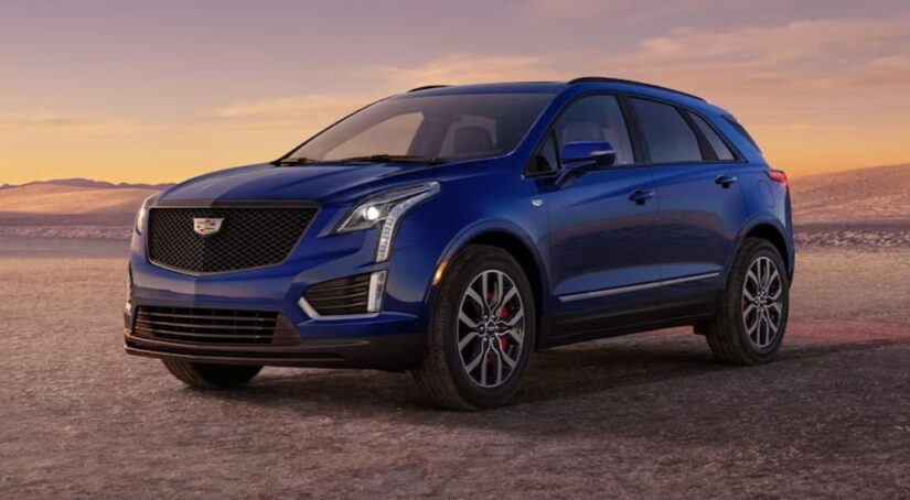 A blue 2024 Cadillac XT5 is shown parked off-road after visiting a Cadillac dealer.