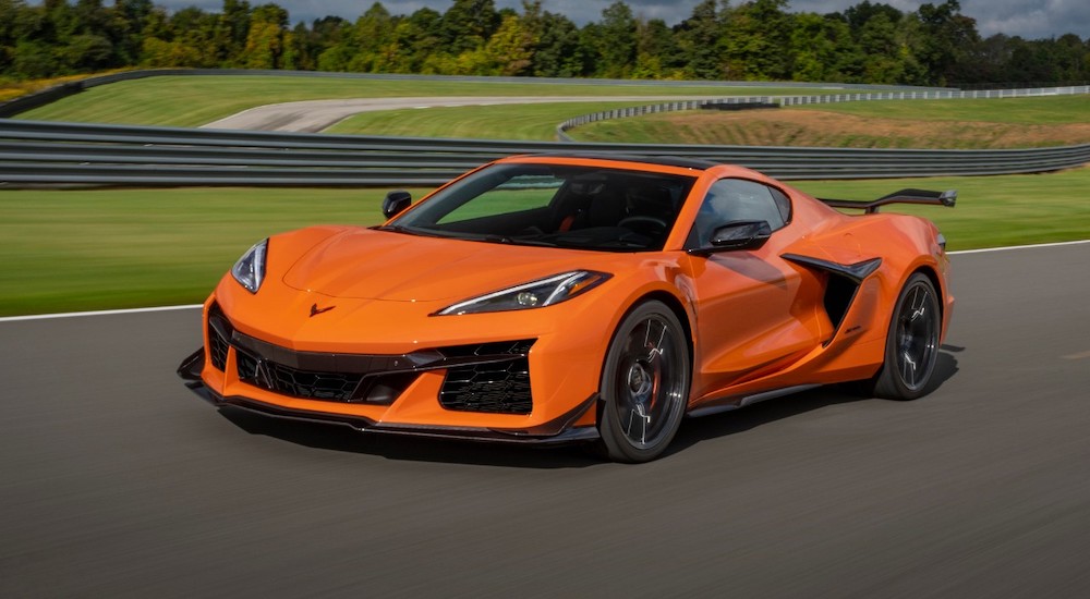 An orange 2024 Chevy Corvette Z06 is shown driving down a track after visiting a Chevy dealer.