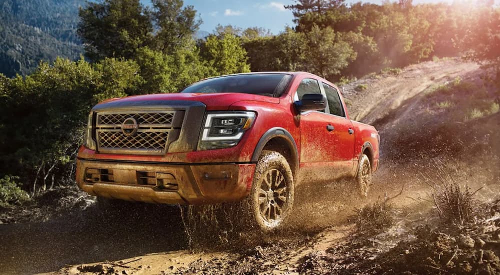 A red 2024 Nissan Titan kicking up mud while off-roading.