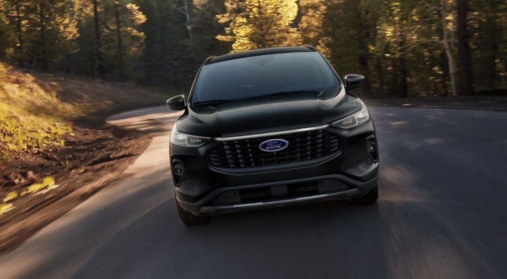 A black 2024 Ford Escape is shown driving from a front angle.