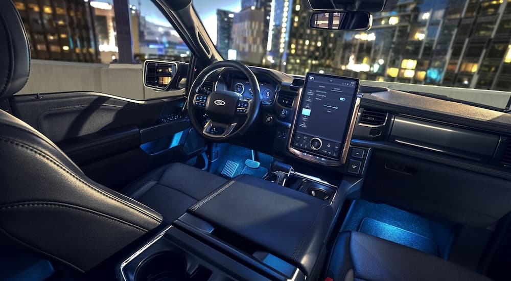 Blue ambient lighting in the cabin of a 2024 Ford F-150 Lightning being compared to a 2024 Tesla Cybertruck.