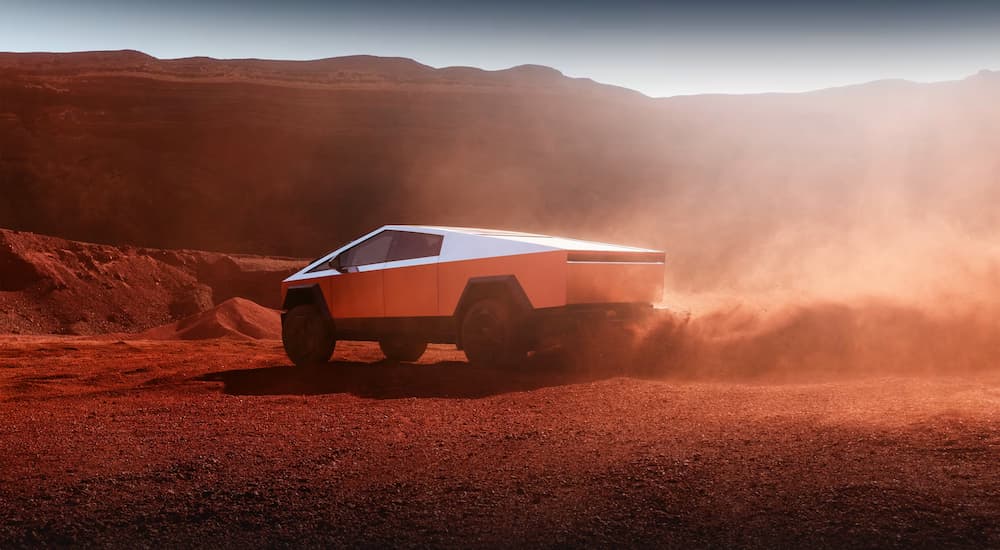 A 2024 Tesla Cybertruck kicking up dirt while off-roading in a red haze.