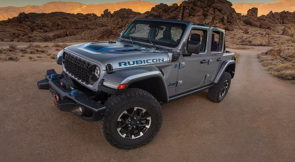 A silver 2024 Jeep Wrangler Rubicon is shown driving off-road.