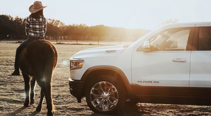A white 2024 Ram 1500 is shown parked near a horse.